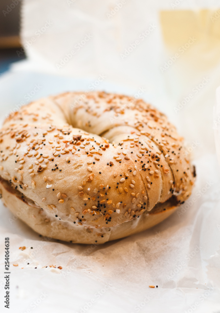 Freshly baked Bagel with sesame, poppyseed topping and cream cheese spread and lox from coffee shop, cafe or bakery in Williamsburg, Brooklyn, New York City, close up with selective focus