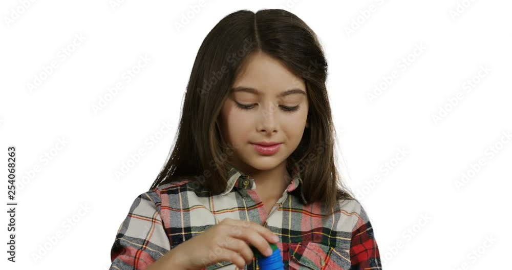 Close up of the Caucasian pretty small schoolgirl with a long hair blowing soap bubbles on the white background. Close up of the Caucasian pretty small schoolgirl with a long hair blowing soap bubbles on the white background.