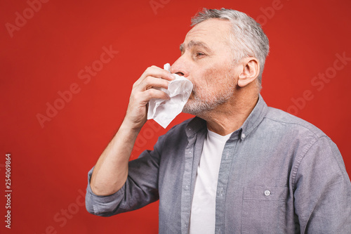 Sick senior man blowing his nose with tissue. having flu, aller