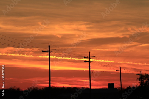 Sunset with power lines silhouettes with a colorful sky. © Stockphotoman