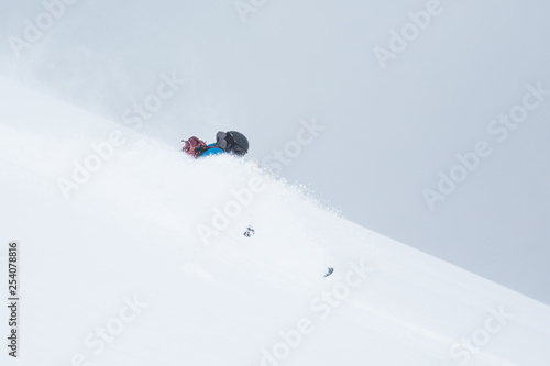 Backcountry skier in blue with backpack turning through deep powder snow of Hokkaido Japan.