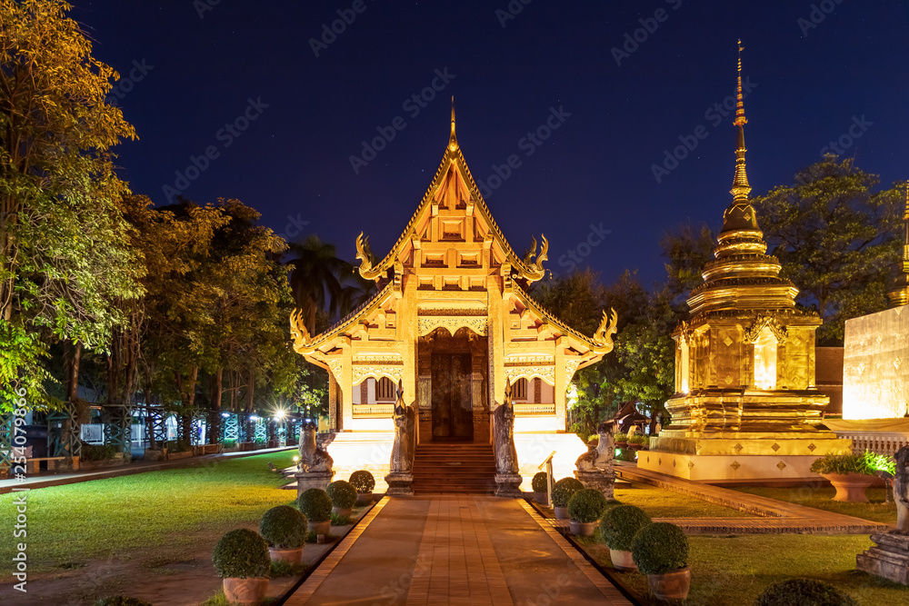 Chapel and golden pagoda at Wat Phra Singh Woramahawihan in Chiang Mai at twilight or night with stars in sky