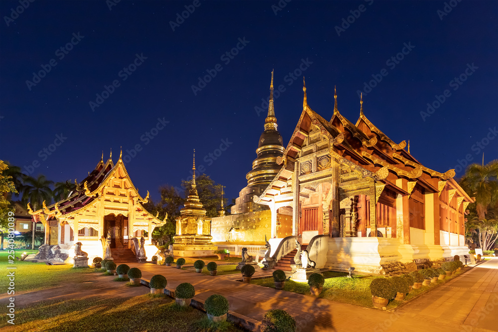 Naklejka premium Chapel and golden pagoda at Wat Phra Singh Woramahawihan in Chiang Mai at twilight or night with stars in sky