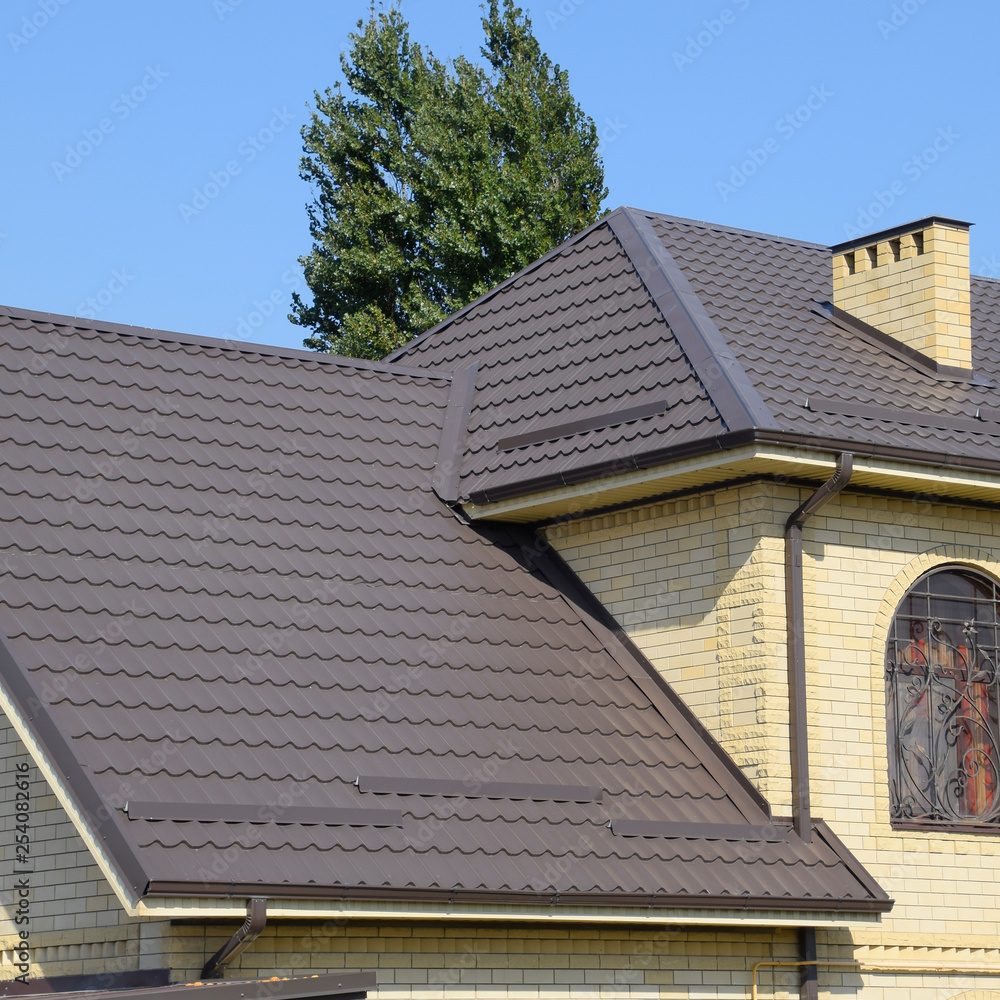 House of yellow brick and brown corrugated roof made of metal. Lattices on the windows. House of yellow brick and brown corrugated roof made of metal. Lattices on the windows.