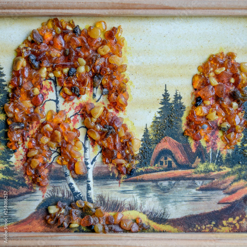 Picture of an amber stone. Crafts made of amber. Landscape house by the river photo