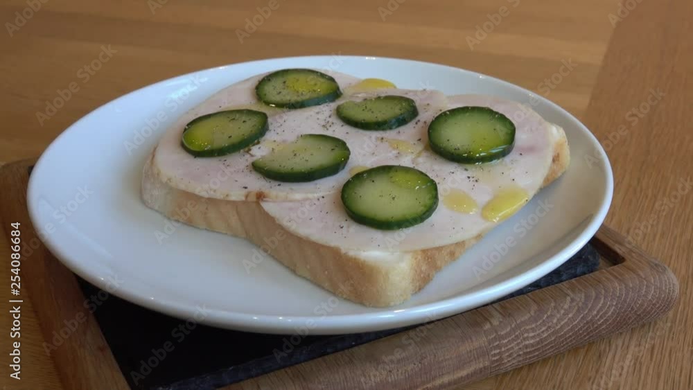 Open Sandwich - Chicken and cucumber, with black pepper and drizzled with olive oil. Shot zooms out and pans across to reveal full sandwich. Open Sandwich - Chicken and cucumber, with black pepper and drizzled with olive oil. Shot zooms out and pans across to reveal full sandwich.