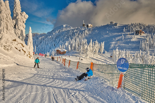 Poiana Brasov, Romania -16 January 2019: Skiers and snowboarders enjoy the ski slopes whit forest covered in snow on winter season,Romania,Europe photo