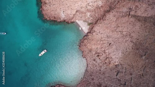Aerial cenital plane shot of a little beach and a yacht in Partida Island, Archipielago Espritu Santo National Park, Baja California Sur. photo