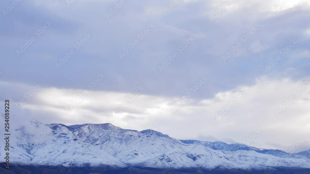 Blue snowcapped mountain at dusk surrounded by clouds in Arizona. Daylight. February. Blue snowcapped mountain at dusk surrounded by clouds in Arizona. Daylight. February.
