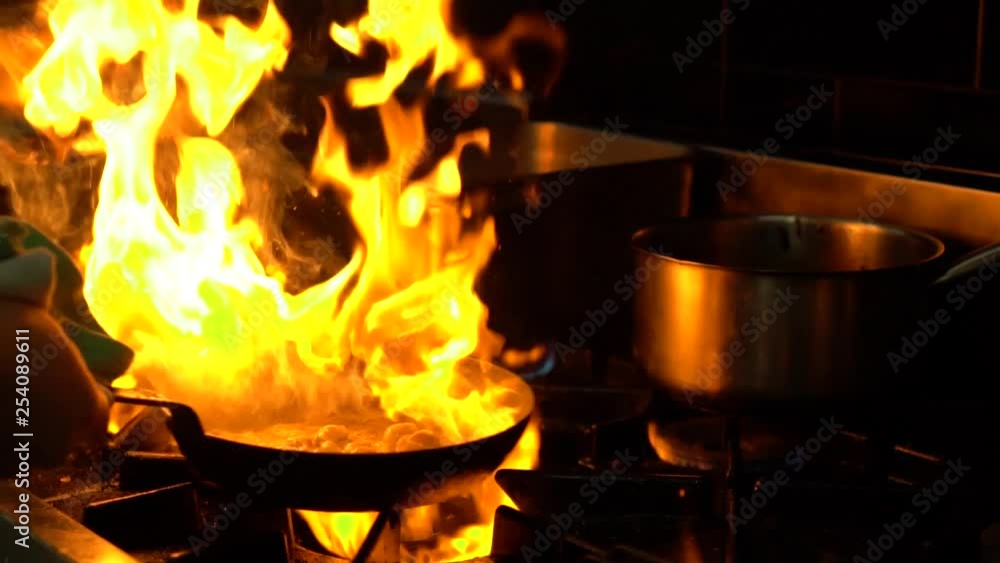 SLOWMO - Chef in a luxury restaurant kitchen flame frying seafood - CLOSE UP SLOWMO - Chef in a luxury restaurant kitchen flame frying seafood - CLOSE UP