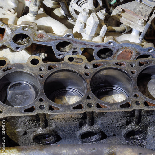 The cylinder block of the four-cylinder engine. Disassembled motor vehicle for repair. Parts in engine oil. Car engine repair in the service