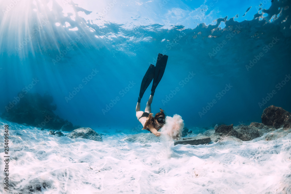 Woman freediver with sand over sandy sea with fins. Freediving underwater in blue ocean