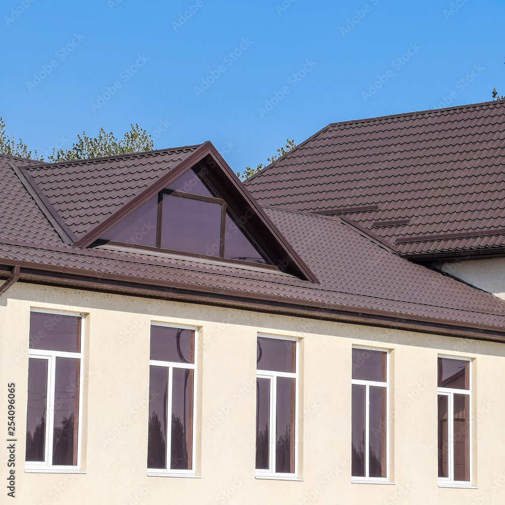 House with plastic windows and roof of corrugated sheet. Roofing of metal profile wavy shape on the house with plastic windows