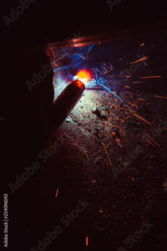 Arc welding. Welding of two metal plates in inert gases. MIG / MAG. A bright flash of light and a sheaf of sparks.