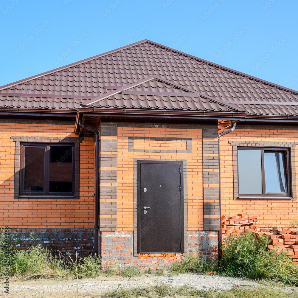 The house with plastic windows and a roof of corrugated sheet. Roofing of metal profile wavy shape on the house with plastic windows The house with plastic windows and a roof of corrugated sheet. Roofing of metal profile wavy shape on the house with plastic windows