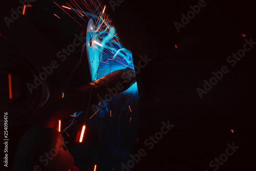 Fototapeta Naklejka Na Ścianę i Meble -  Arc welding. Welding of two metal plates in inert gases. MIG / MAG. A bright flash of light and a sheaf of sparks.