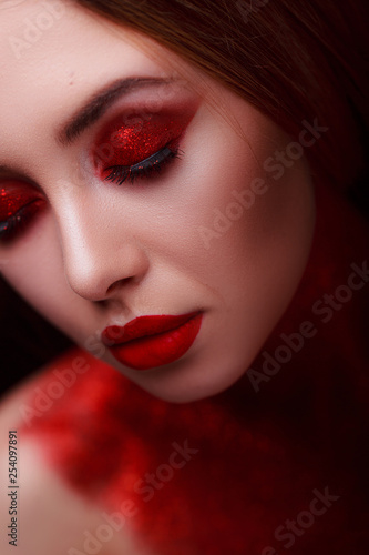 Red makeup in the style of beauty. Bright lips and eyes. Portrait of a beautiful young girl. Journal detailed skin retouching. Expressive eyebrows. Huge eyelashes. Neon shadows.