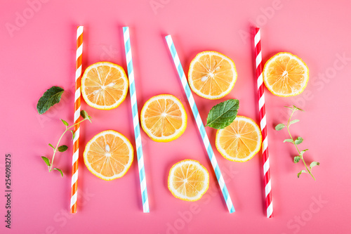 Fototapeta Naklejka Na Ścianę i Meble -  Colored straws and fresh lemon slices, mint leaves on a pink background