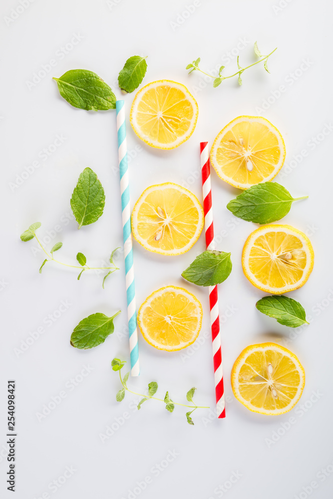 Colorful drinking paper straws and mint leaves, lemon slices on a white background Colorful drinking paper straws and mint leaves, lemon slices on a white background