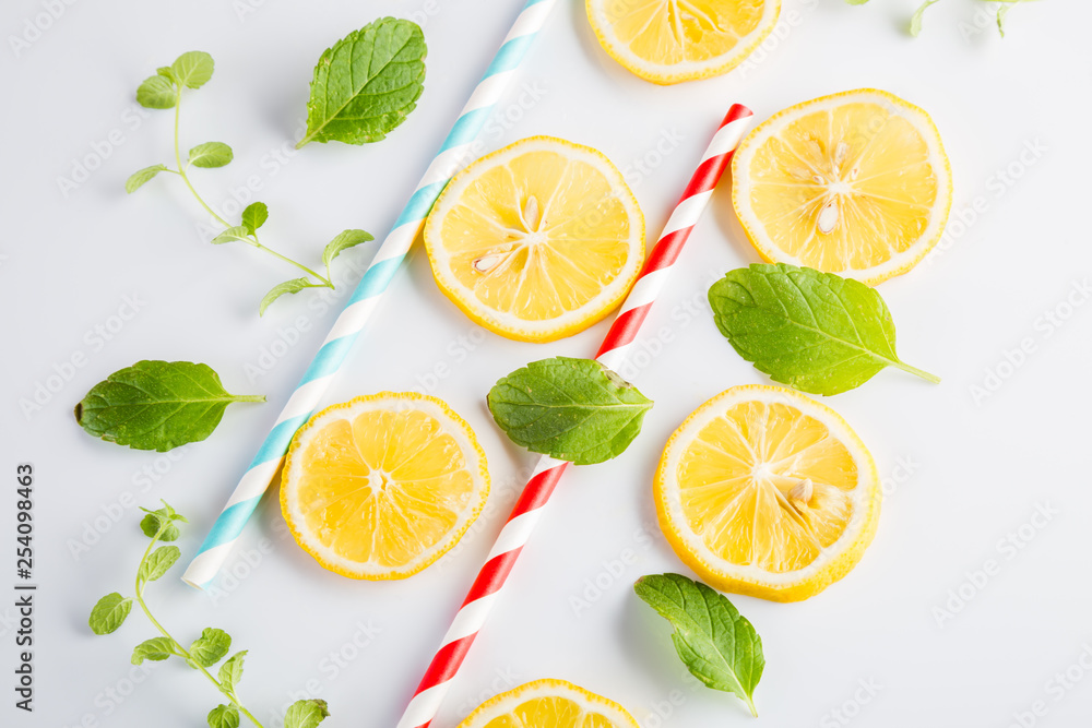 Colorful drinking paper straws and mint leaves, lemon slices on a white background Colorful drinking paper straws and mint leaves, lemon slices on a white background