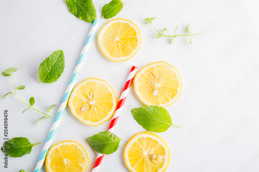 Colorful drinking paper straws and mint leaves, lemon slices on a white background Colorful drinking paper straws and mint leaves, lemon slices on a white background