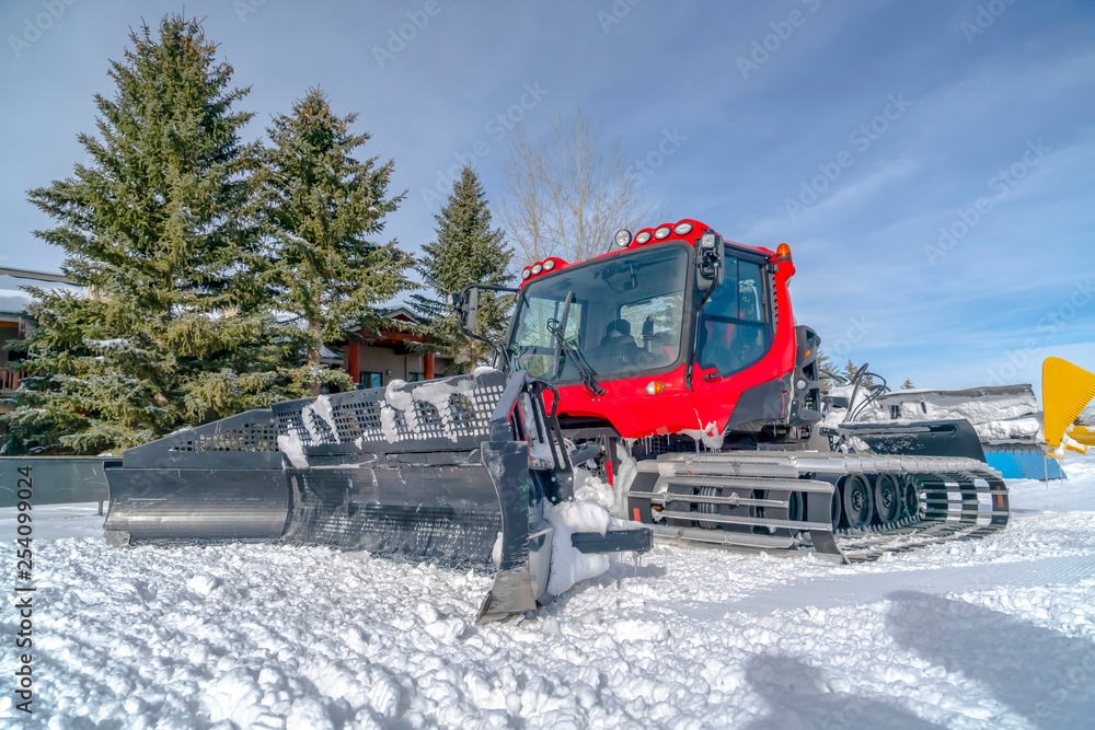 Snow groomer against snow trees and sky in Utah Snow groomer against snow trees and sky in Utah
