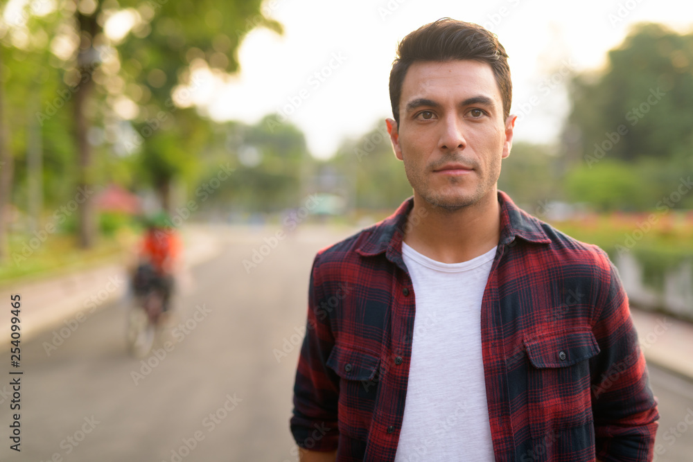 Young handsome Hispanic hipster man thinking at the park Young handsome Hispanic hipster man thinking at the park