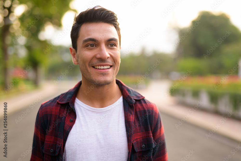 Face of happy young Hispanic hipster man thinking at the park Face of happy young Hispanic hipster man thinking at the park