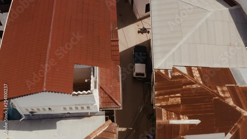 Fly over Zanzibar Stone Town old narrow street with rusty roofs and rooftop restaurant photo