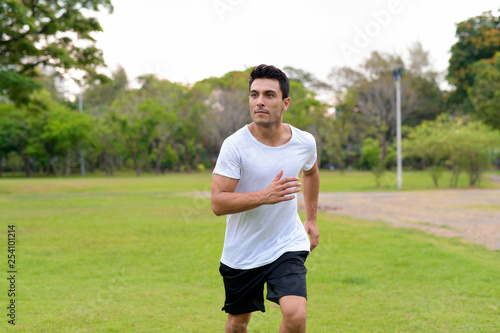 Young handsome Hispanic man jogging in the park outdoors