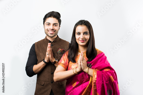 Indian couple welcoming with namaskara pose or both hands folded while wearing traditional festival clothing, isolated over white background photo