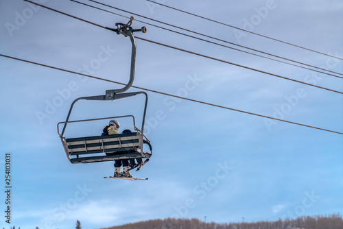 Woman and child on ski lift with view of blue sky