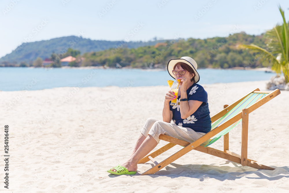 Mature woman on the beach drinking cocktail in a lounge