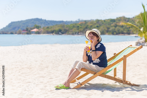 Mature woman on the beach drinking cocktail in a lounge © PhotoSeka