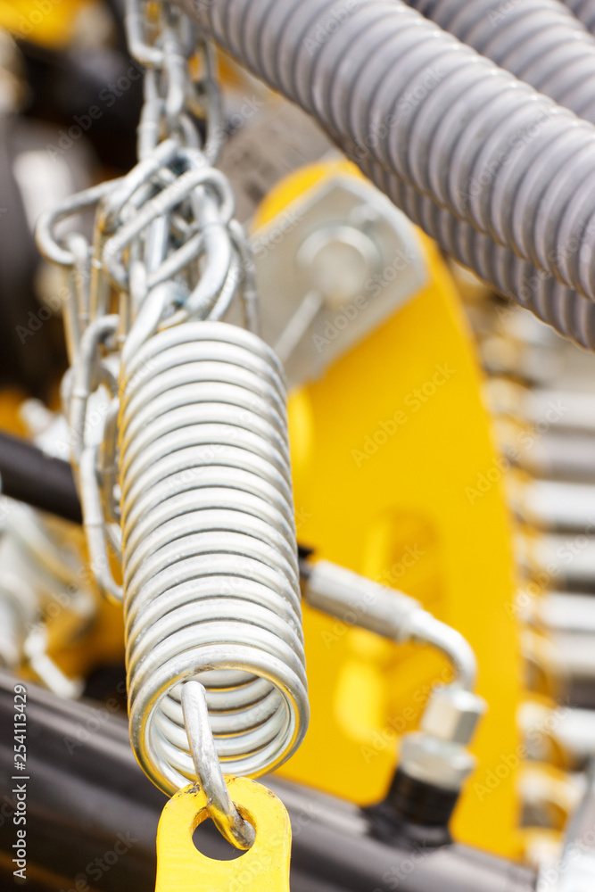 Steel spring as detail of industrial or agricultural machinery, technology and engineering concept Steel spring as detail of industrial or agricultural machinery, technology and engineering concept
