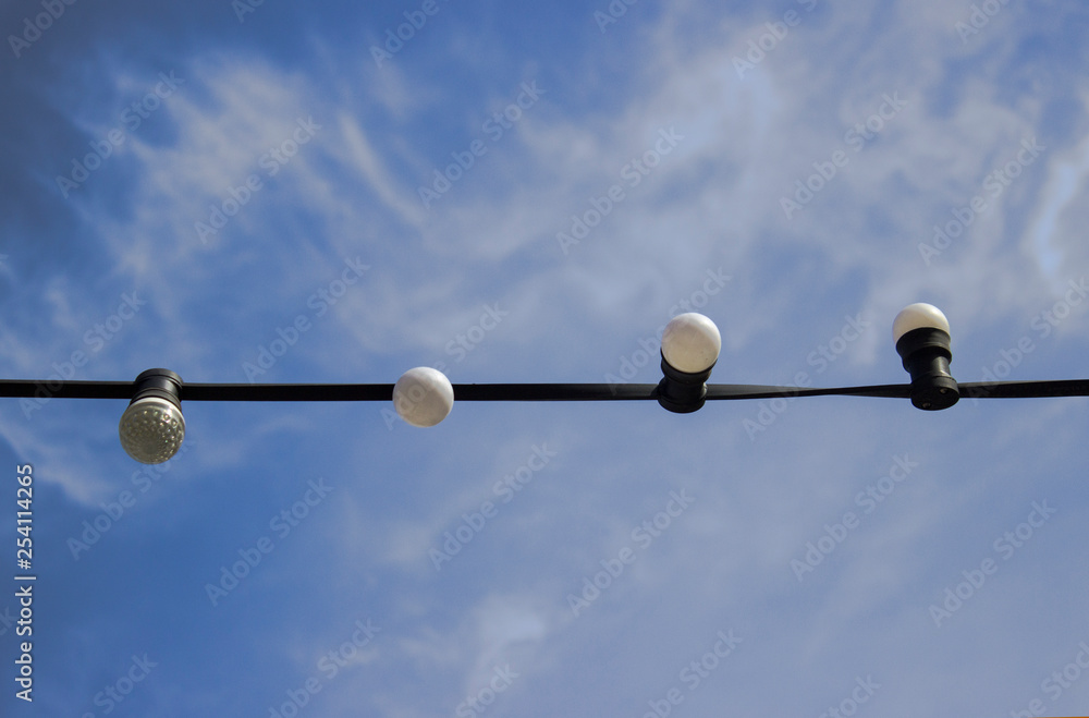 pigeons White street lights hanging on a long straight black wire on a blue background of it and white clouds close up on a clear dayon a wire pigeons White street lights hanging on a long straight black wire on a blue background of it and white clouds close up on a clear dayon a wire