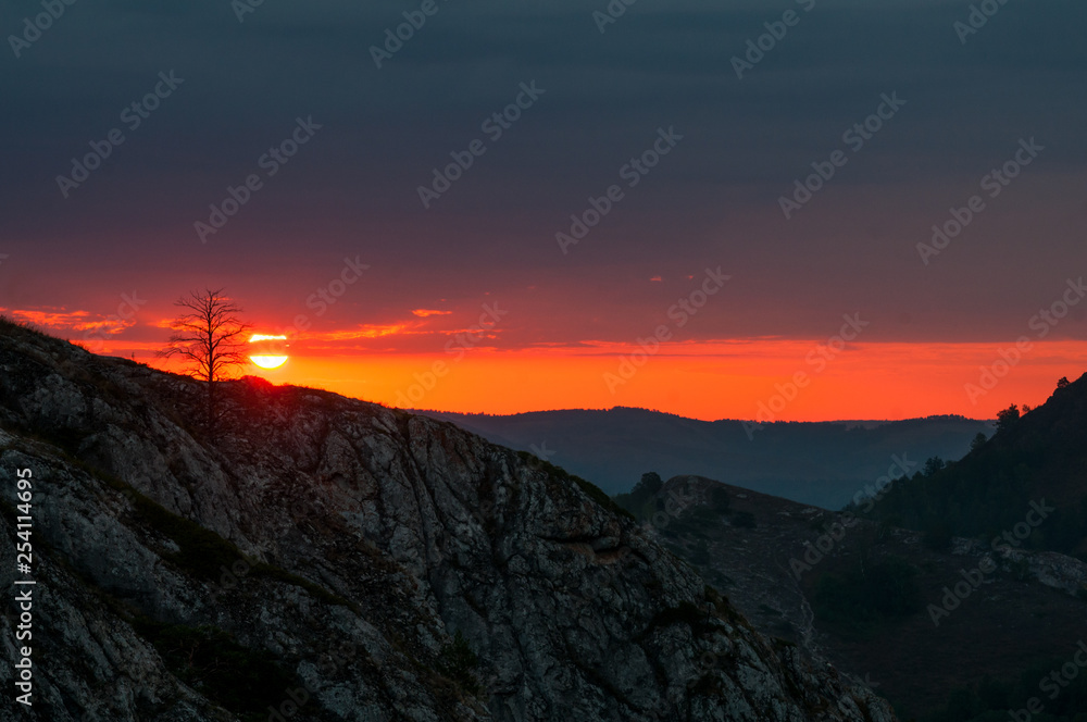 bright red dawn in the mountains in a windy, cloudy morning, the sun rises from the horizon bright red dawn in the mountains in a windy, cloudy morning, the sun rises from the horizon