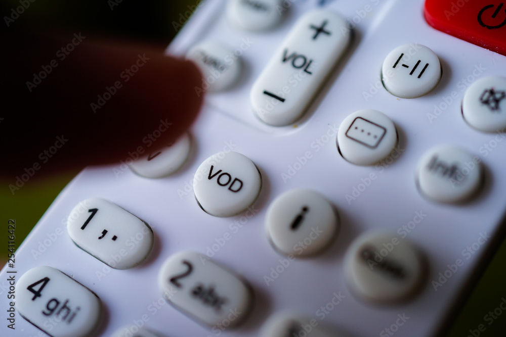 Man holding tv remote commander and press VOD button Man holding tv remote commander and press VOD button