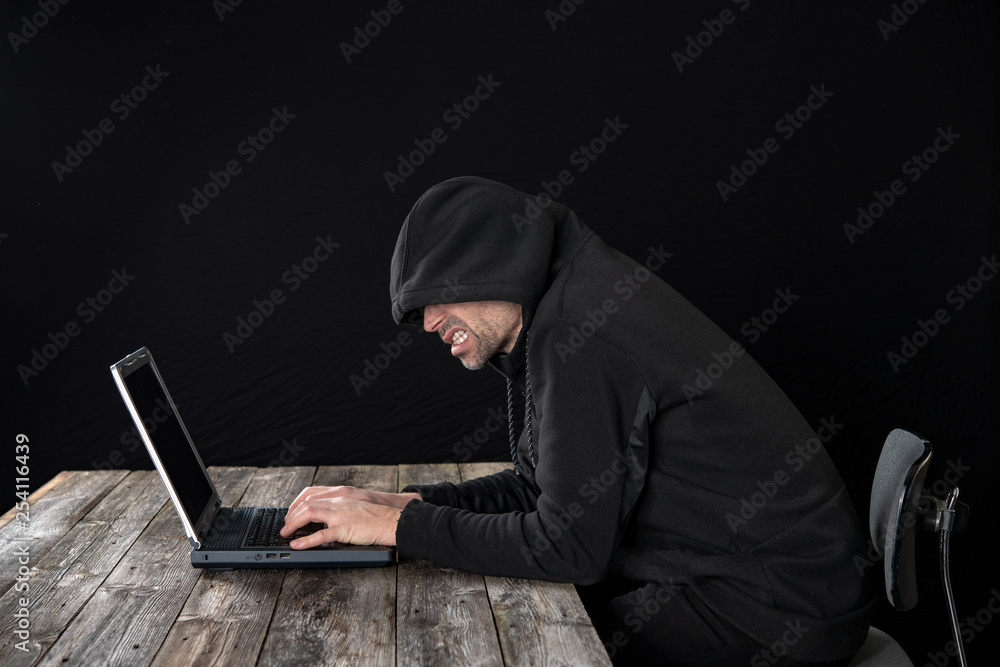 hacker in black hoody with laptop hacker in black hoody with laptop
