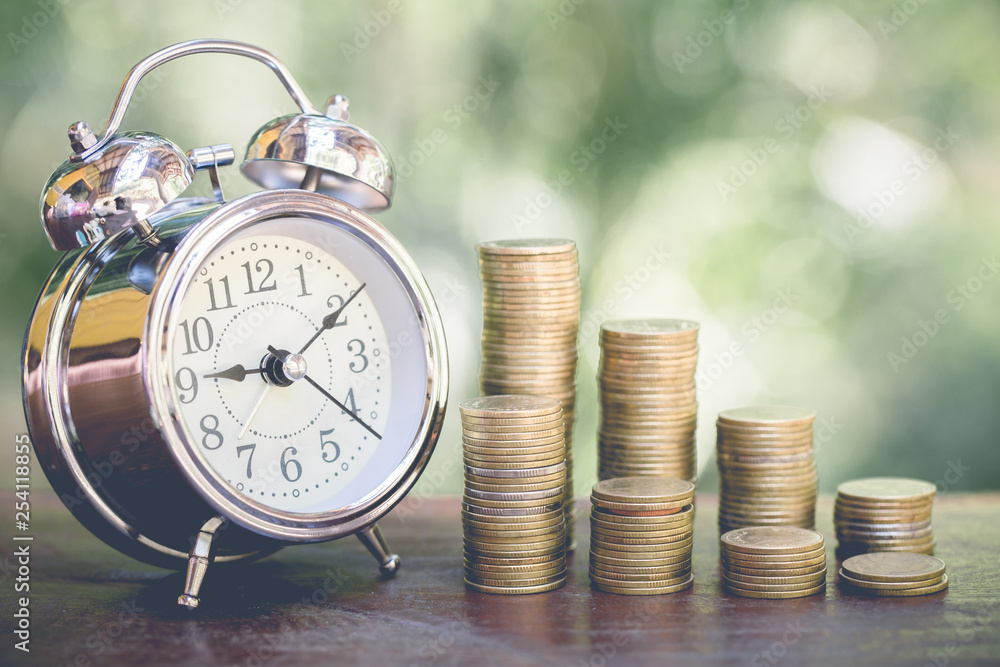 Alarm clock and step of coins stacks on table, time for savings money concept, banking and business, vintage tone. Alarm clock and step of coins stacks on table, time for savings money concept, banking and business, vintage tone.