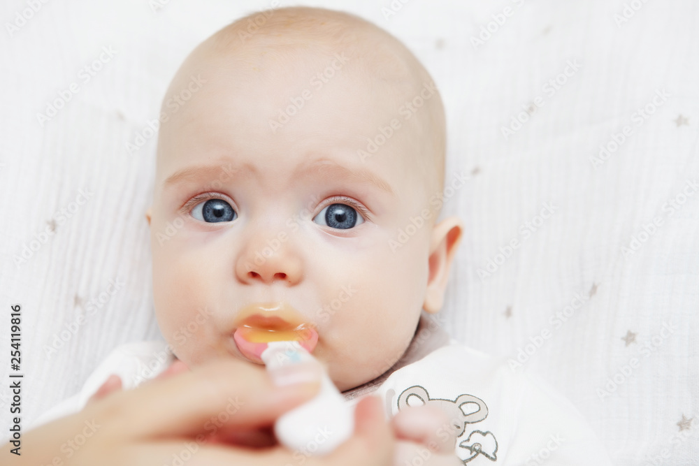 Beautiful Lovely five-month baby girl eating with a spoon. Healthy food. Maternal care. Childcare. Close-up. Beautiful Lovely five-month baby girl eating with a spoon. Healthy food. Maternal care. Childcare. Close-up.