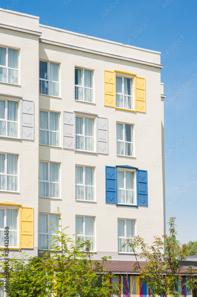 View to facade of building with windows with colored wooden shutters.