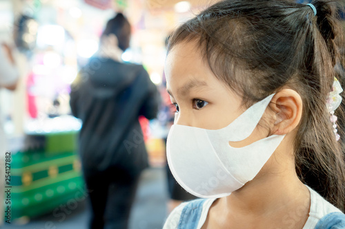 Cute asian child girl wearing protection mask to against air smog pollution with PM 2.5 in the city