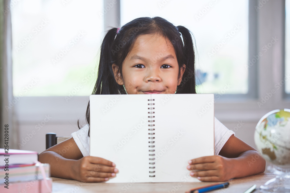 Back to school. Cute asian child girl holding a book in the classroom Back to school. Cute asian child girl holding a book in the classroom