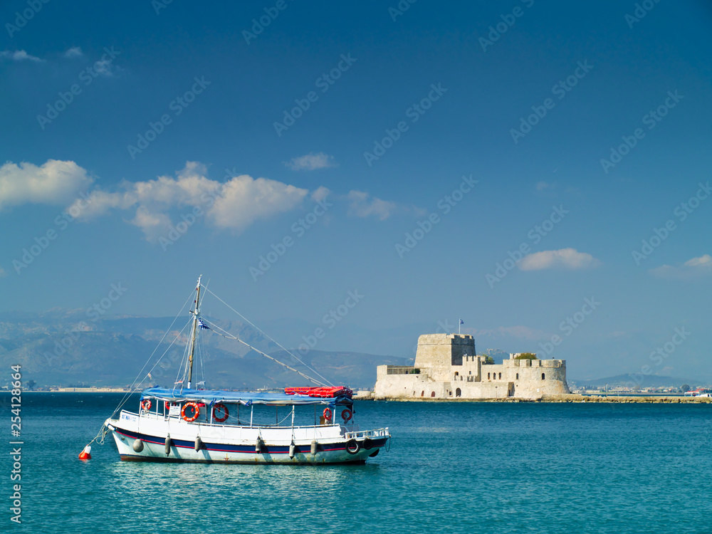Small touristic ship in Nafplio Greece, with mpourtzi castle in background. A bright sunny day.