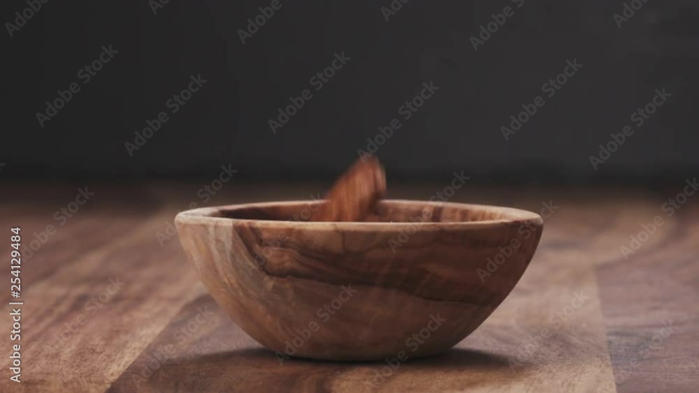 Slow motion dried pecan nuts falling into wood bowl Slow motion dried pecan nuts falling into wood bowl