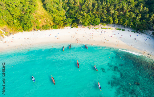 View from above, stunning aerial view of a beautiful tropical beach with white sand and turquoise clear water, long-tail boats and people sunbathing, Banana beach, Phuket, Thailand.