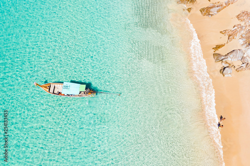 Obraz na płótnie View from above, stunning aerial view of two people walking on a beautiful tropical beach with white sand, turquoise clear water and a traditional long-tail boat. Banana beach, Phuket, Thailand. w salonie