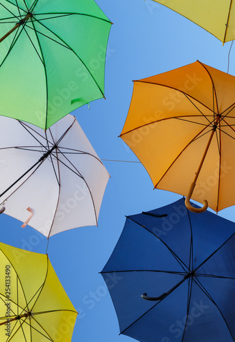 Colourful sun umbrellas against the blue sky. Street decoration. Vertical photo.