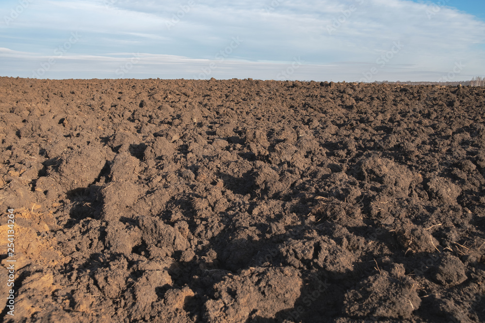 brown plowed ground under a gray sky with clouds, field plowed for planting to the horizon